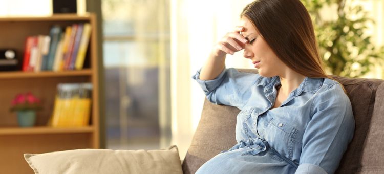 Zirytowana kobieta w ciąży siedzi na kanapie w salonie w domu