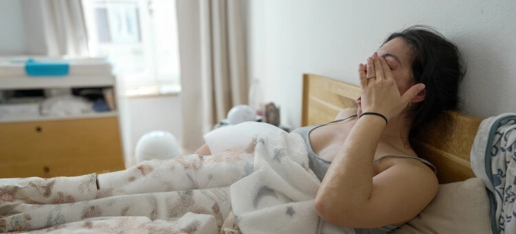 Zmęczona kobieta leżąca w łóżku w okresie połogu po porodzie