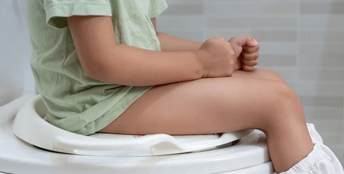 Małe dziecko siedzące na toalecie podczas biegunki