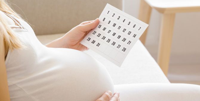 kobieta w ciąży z kalendarzem trwania ciąży