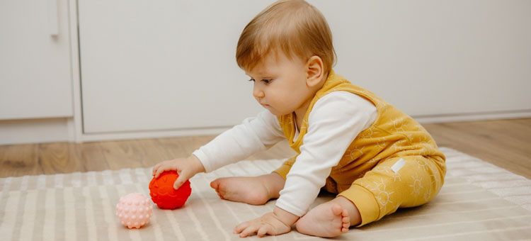 małe dziecko bawiące się na dywanie