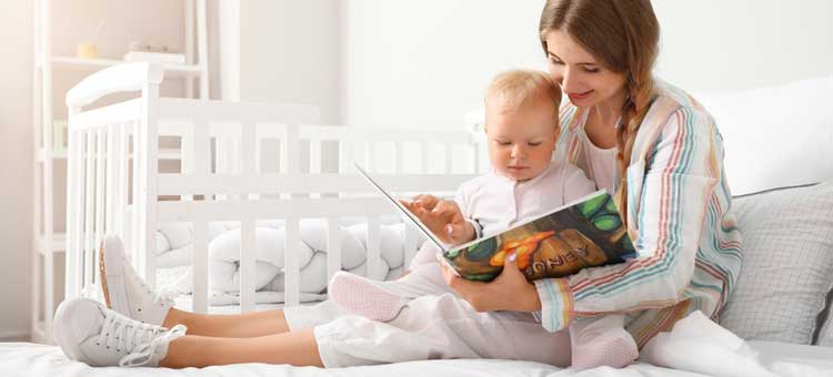 kobieta z niemowlakiem na kolanach czyta książeczkę