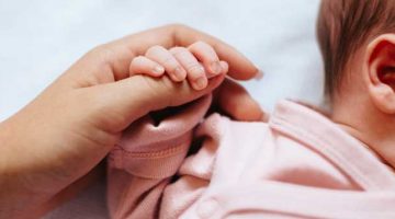 niemowlę zaciskające rączkę wokół kciuka dorosłej osoby