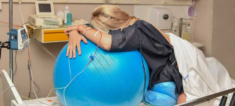 kobieta na łóżku porodowym z piłką