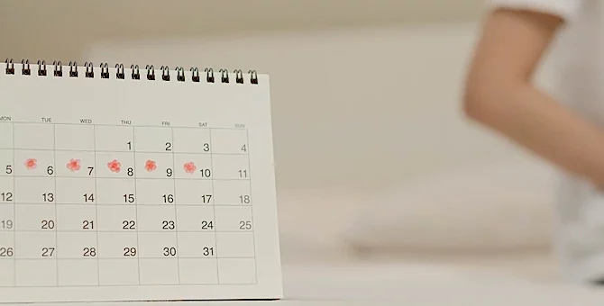 Kalendarz miesiączkowy, w tle siedząca kobieta