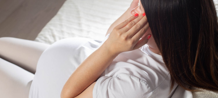 kobieta w ciąży dotyka skroni bolącej głowy