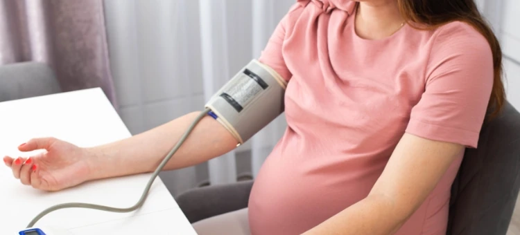 Kobieta w ciąży mierzy ciśnienie z ręką na stole