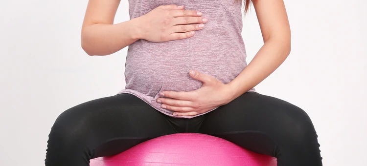 Młoda kobieta w ciąży ćwiczy na piłce, dbając o zdrowie
