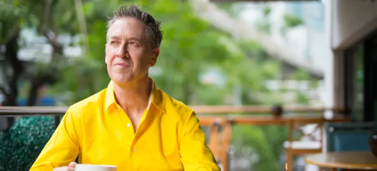 Mężczyzna w średnim wieku siedzący w kawiarni i zastanawiający się