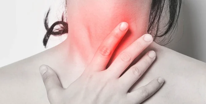 Kobieta dotykająca swojej szyi, co sugeruje ból gardła