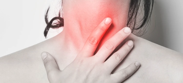 Kobieta dotykająca swojej szyi, co sugeruje ból gardła