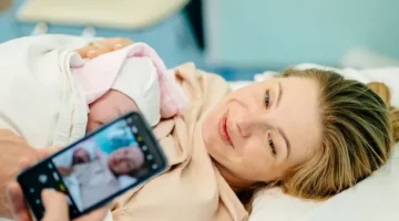 Szczęśliwa kobieta i ojciec wspierający ją po urodzeniu dziecka, robiący pierwsze zdjęcie swojego dziecka w sali porodowej
