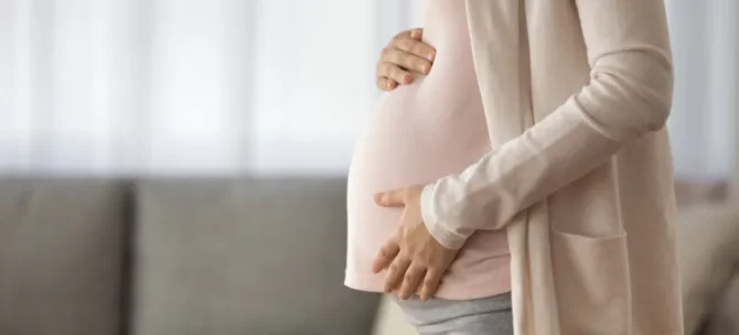 Młoda kobieta dotyka brzucha, ciesząc się ostatnimi miesiącami ciąży, gotowa do porodu