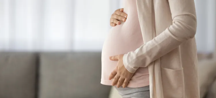 Młoda kobieta dotyka brzucha, ciesząc się ostatnimi miesiącami ciąży, gotowa do porodu