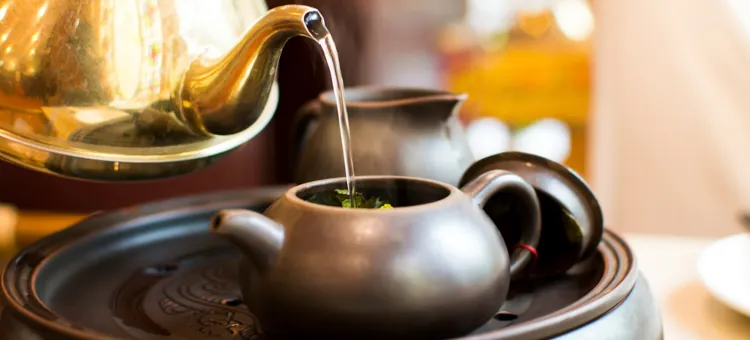 Gorąca woda jest wlewana do ceramicznego dzbanka na herbatę