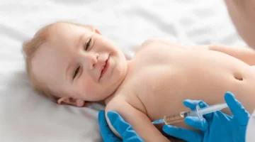 Lekarz pediatra podaje szczepionkę małemu uśmiechniętemu dziecku