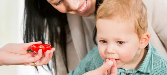 Młoda kobieta z dzieckiem u lekarza homeopaty, który podaje dziecku homeopatyczne tabletki