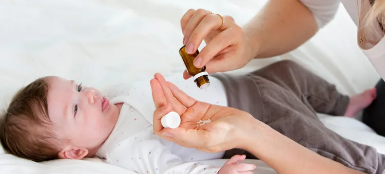 Matka podaje dziecku lek homeopatyczny w postaci globulek