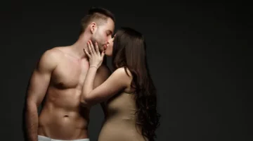 Kobieta w ciąży całuje swojego rozebranego męża