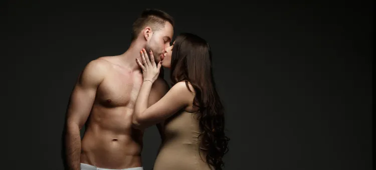 Kobieta w ciąży całuje swojego rozebranego męża