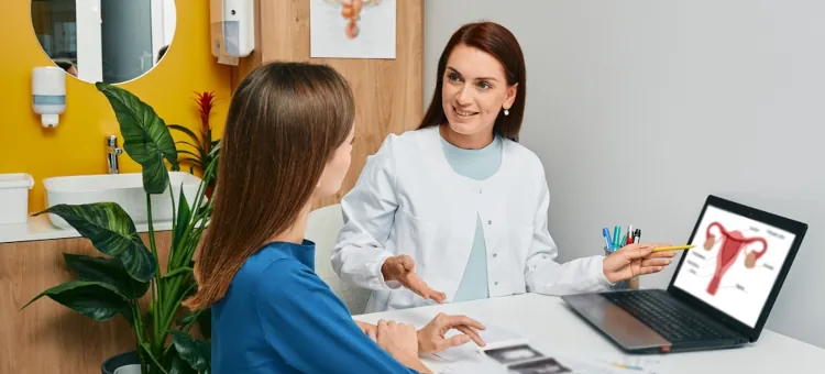 Konsultacja u lekarza ginekologa w gabinecie, lekarka rozmawia z pacjentką na temat zdrowia oraz pracy jajników, pokazuje schemat żeńskiego układu rozrodczego na komputerze