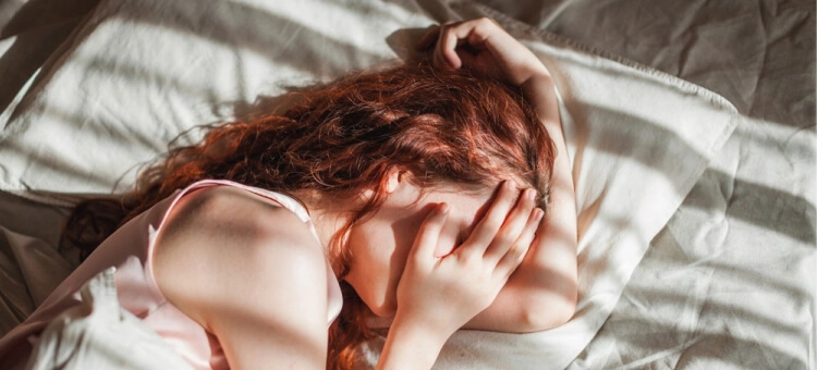 Opóźnienie miesiączki a antykoncepcja hormonalna i karmienie piersią Kobieta leżąca w łóżku – złe samopoczucie i objawy związane z opóźnieniem miesiączki
