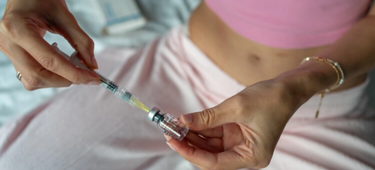Kobieta przygotowująca zastrzyk hormonalny, trzymająca strzykawkę i fiolkę z lekiem