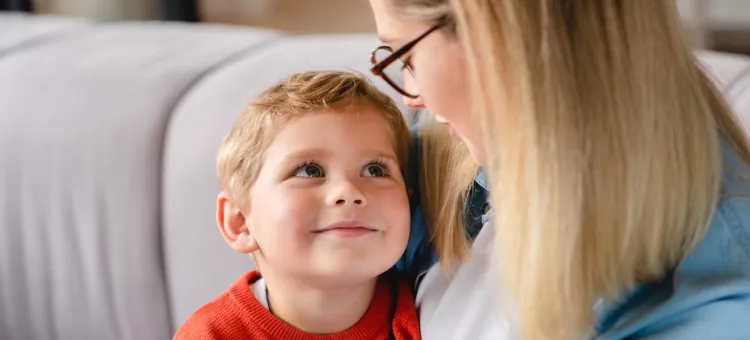 Mama w okularach mówi do małego chłopca w czerwonym stroju