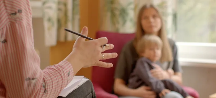 Psychologiczne konsultacje rodzinne w gabinecie, w tle mama z dzieckiem w spektrum autyzmu