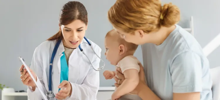 Lekarz pediatra rozmawia z młodą matką trzymającą na rękach niemowlę