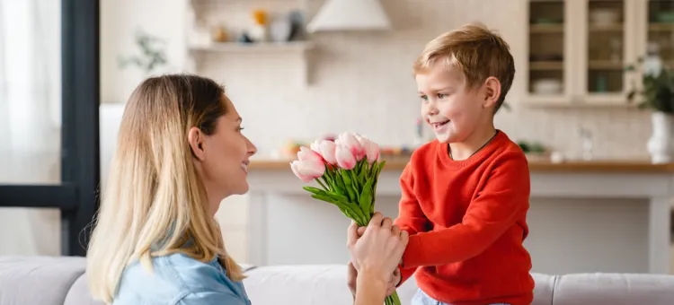 Radosny chłopiec przekazuje bukiet tulipanów uśmiechniętej mamie na Dzień Matki