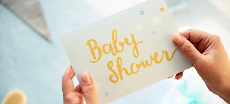 Bilecik z żółtym napisem Baby Shower dzierżony przez parę dłoni