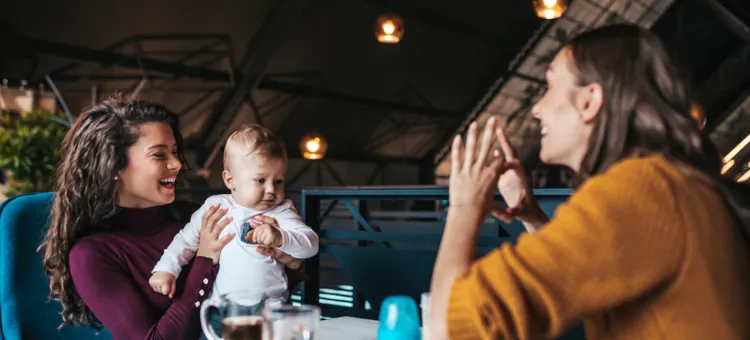 Radosna mama i jej przyjaciółka spędzają czas z niemowlakiem w kawiarni