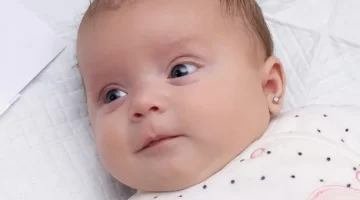 Zbliżenie twarzy dziecka spogladajacego w bok, z kolczykiem w uchu