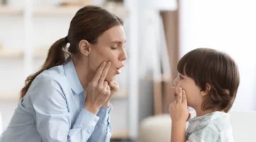 Specjalistka logopedii pokazuje dziecku, jak kształtować poprawne dźwięki mowy