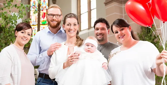 Szczęśliwi bliscy radują się z uroczystości chrztu maleńkiej osoby w świątyni, a jedna z osób dzierży balony