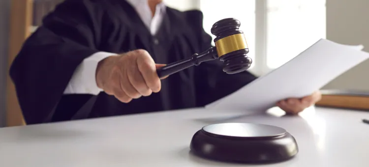 Sędzia trzymający ciężki młotek przed aktami sprawy o np. ustalenie ojcostwa