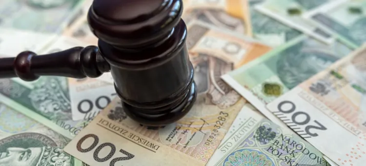 Sędziowski młotek spoczywa na stosie wartościowych banknotów, symbolizując zakończenie sprawy dotyczącej finansów, np. alimentów