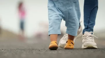 Drobne nóżki dziecka w sandałach towarzyszą dorosłym stopom na spacerze