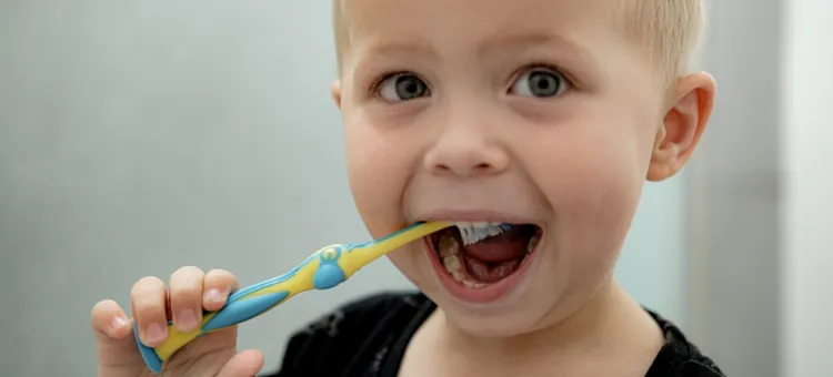 Zęby mleczne – najczęściej zadawane pytania Rozbawiony maluch starannie czyści białe ząbki