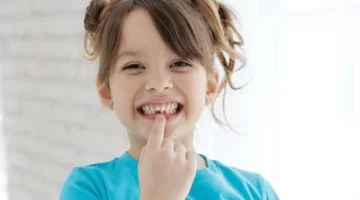 Szczęśliwe dziecko w niebieskiej koszulce prezentuje ubytek w swoim uzębieniu