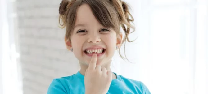 Szczęśliwe dziecko w niebieskiej koszulce prezentuje ubytek w swoim uzębieniu