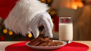 Ręka Mikołaja w białej rękawicy zmierza w kierunku kruchych przysmaków i mleka