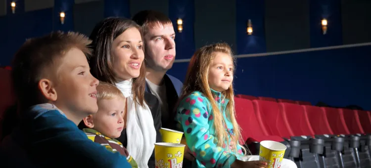 Bliscy członkowie dużej rodziny, siedzący na widowni z popcornem, skupieni na trwającej projekcji