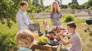 Uśmiechnięci członkowie dużej rodziny cieszą się posiłkiem na świeżym powietrzu w słoneczny dzień