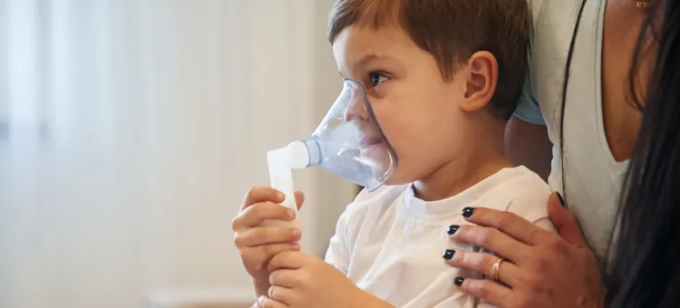 Dziecko otrzymuje wsparcie podczas terapii oddechowej w celu zmniejszenia kaszlu, ręka matki trzyma go za ramię