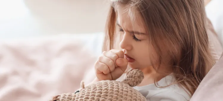 Mała dziewczynka przy ukochanym pluszaku, walcząca z dolegliwościami dróg oddechowych w łóżku