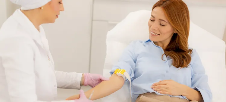 Uśmiechnięta kobieta na fotelu przygotowywana do pobrania krwi przez specjalistę z branży zdrowotnej