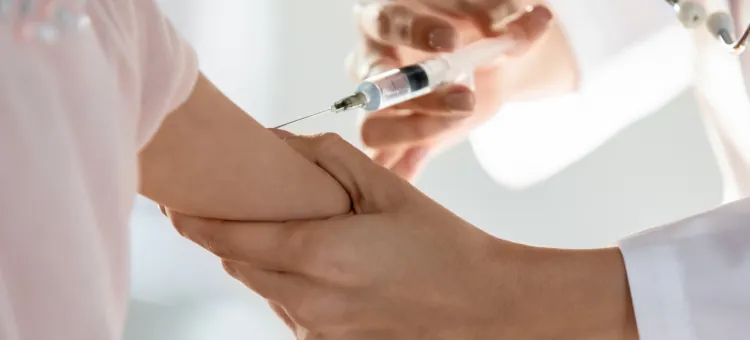 Ramię pacjenta otrzymujące szczepionkę od pracownika służby zdrowia