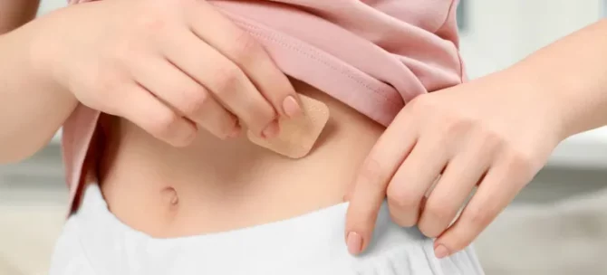 Kobieta delikatnie nakładająca niewielki antykoncepcyjny przylepiec na skórę swojego brzucha